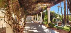A covered walkway with columns, palm trees, and outdoor seating. - Crowne Plaza Phoenix - Chandler Golf Resort by IHG (Chandler)