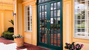 Un bâtiment avec une porte verte, de grandes fenêtres et des plantes en pot.