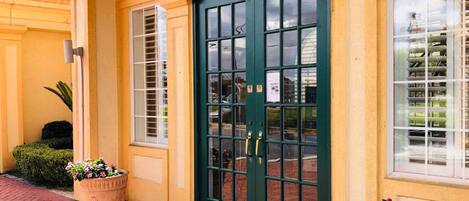A building with a green door, large windows, and potted plants.