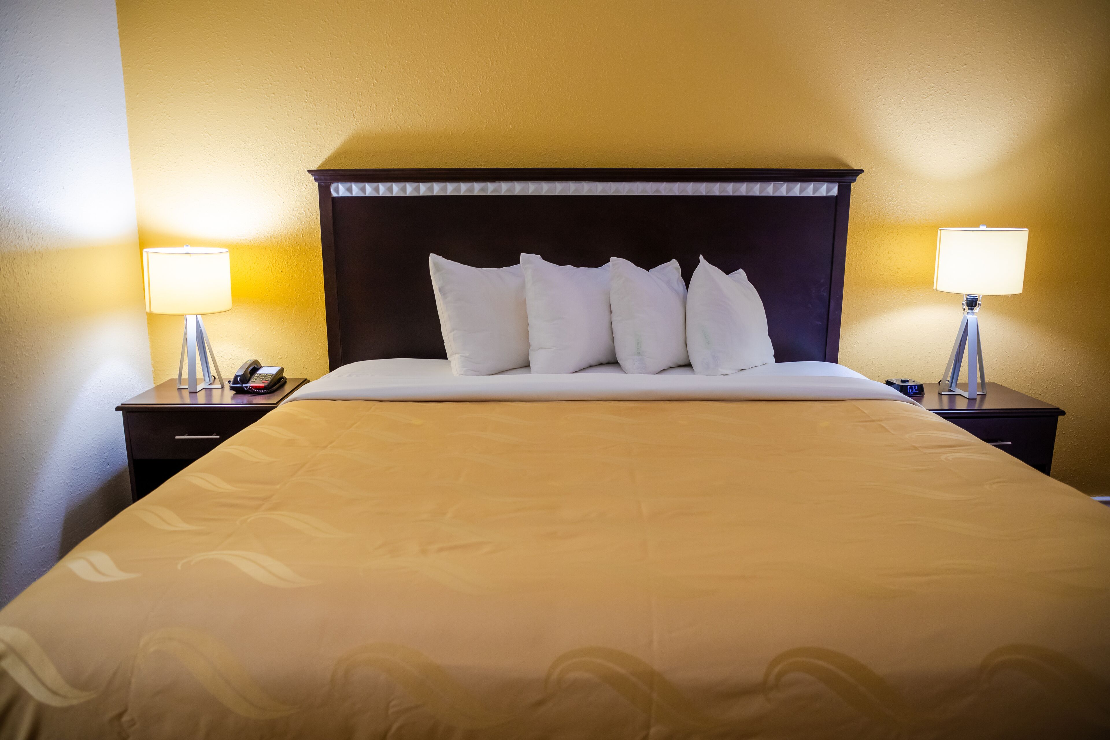 A hotel room with a large bed, two bedside tables, and two lamps.