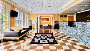 Un hall d’hôtel avec un sol à carreaux, un canapé, une table basse et un téléviseur fixé au mur.