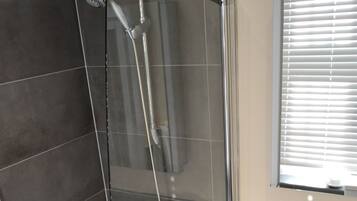 Un baño moderno con ducha envuelta en vidrio, una bañera independiente y un tocador con espejo.