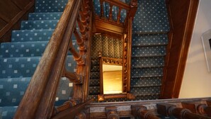 A wooden staircase with a mirror at the top, leading to a room with patterned carpet. - Royal Oxford Hotel (Oxford)