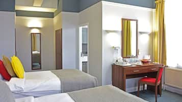 A hotel room with a bed, a desk, a chair, and a mirror.