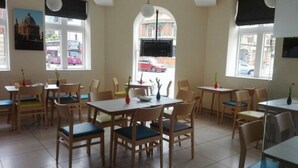 A restaurant with wooden tables and chairs, large windows, and a view of the street outside. - Royal Oxford Hotel (Oxford)
