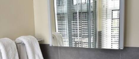 A modern bathroom with a large mirror, a white sink, and two towels hanging on a rack.