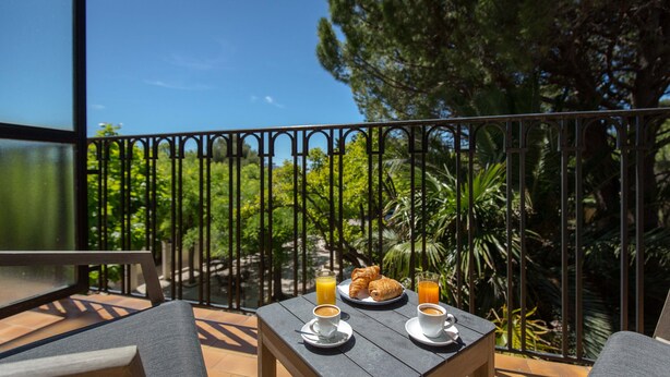 Ein Balkon mit einem Frühstückstisch, mit Croissants, Orangensaft und Kaffee.