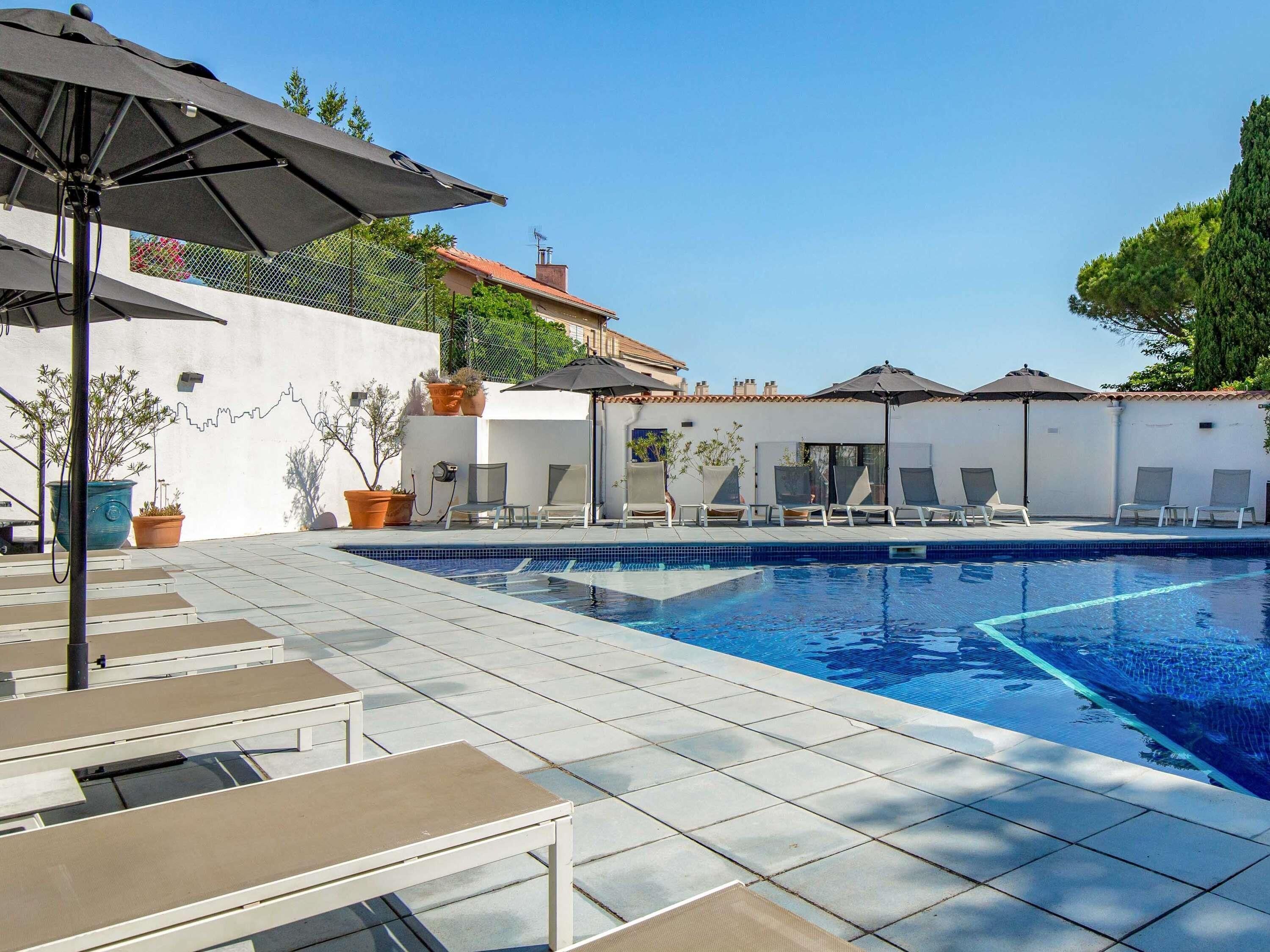 Una piscina al aire libre de temporada, sombrillas