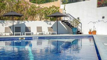 Una piscina al aire libre de temporada, sombrillas