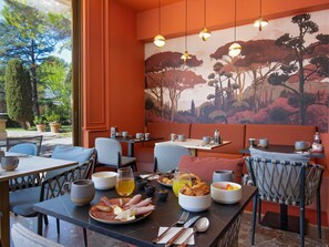 A dining area with tables, chairs, and a mural of trees.