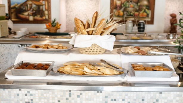 Buffet com diversos alimentos, incluindo pão, doces e frutas.