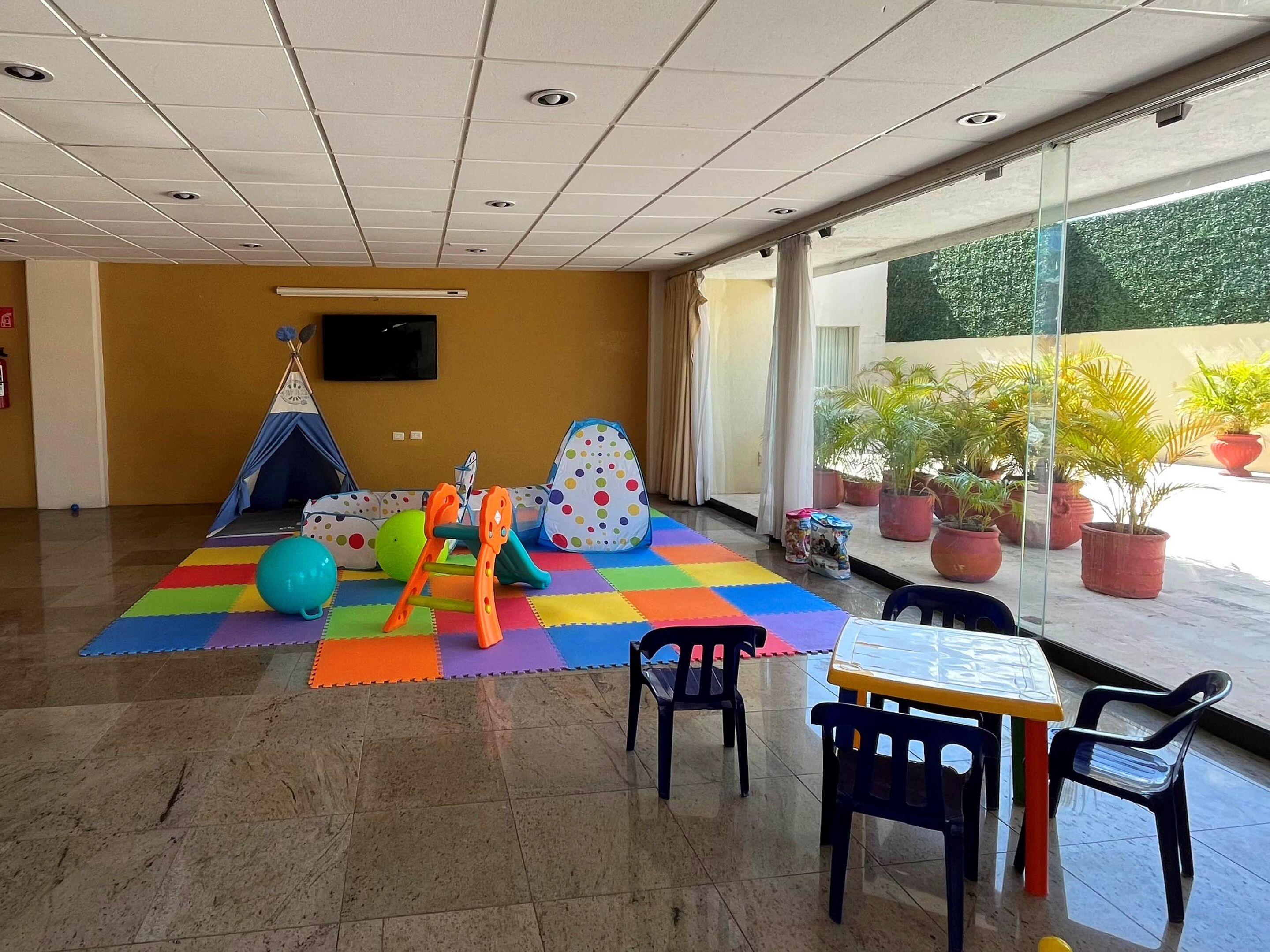 A children's play area with a tent, play structure, and colorful mats.