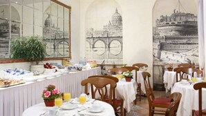 Comedor con mesas dispuestas para el desayuno, que incluye un bufé con diferentes alimentos y un amplio ventanal con vistas a un puente.