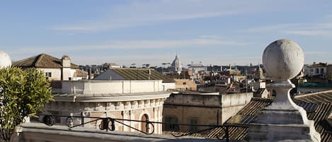 Una terraza con barandilla que da a un paisaje urbano con edificios históricos y una estructura en forma de cúpula.