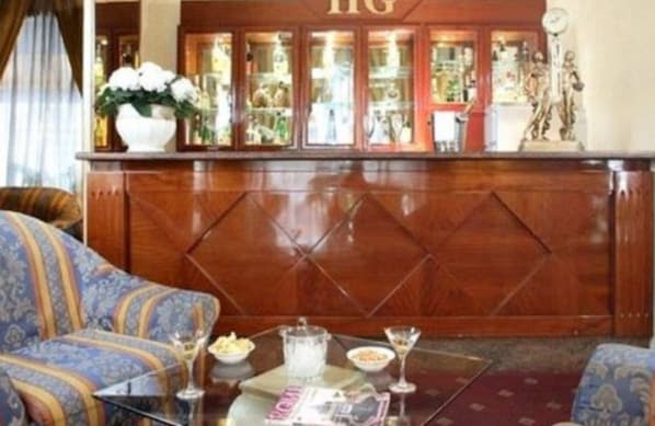 Un coin bar avec un comptoir en bois, un vase avec des fleurs et un magazine sur la table.