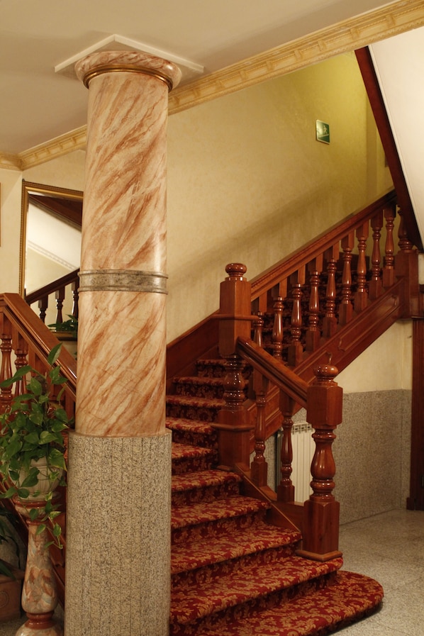 Una imponente escalera con columnas de mármol y barandillas de madera.