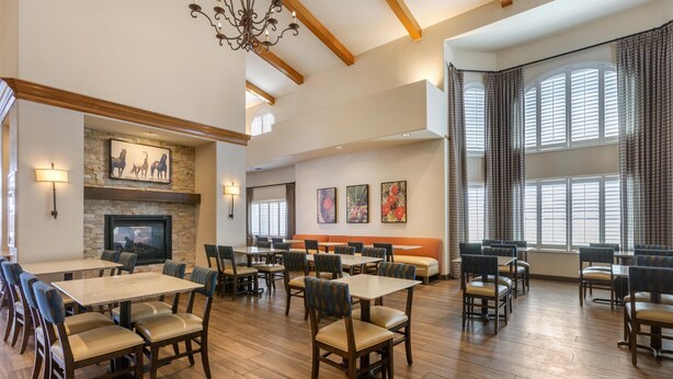 A spacious dining area with multiple tables and chairs, a fireplace, and large windows with curtains. - Best Western Plus A Wayfarer's Inn And Suites (Kingman)