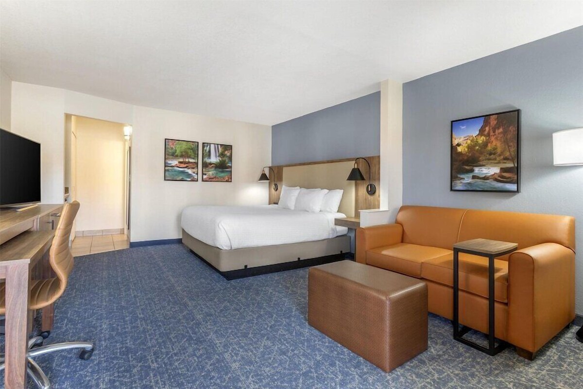 A hotel room with a bed, a sofa, a desk, and a TV.