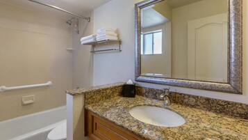 Un baño con lavamanos blanco, encimera de granito y un espejo grande.