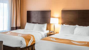 A hotel room with two beds, a nightstand with a lamp, and a view of the outdoors.