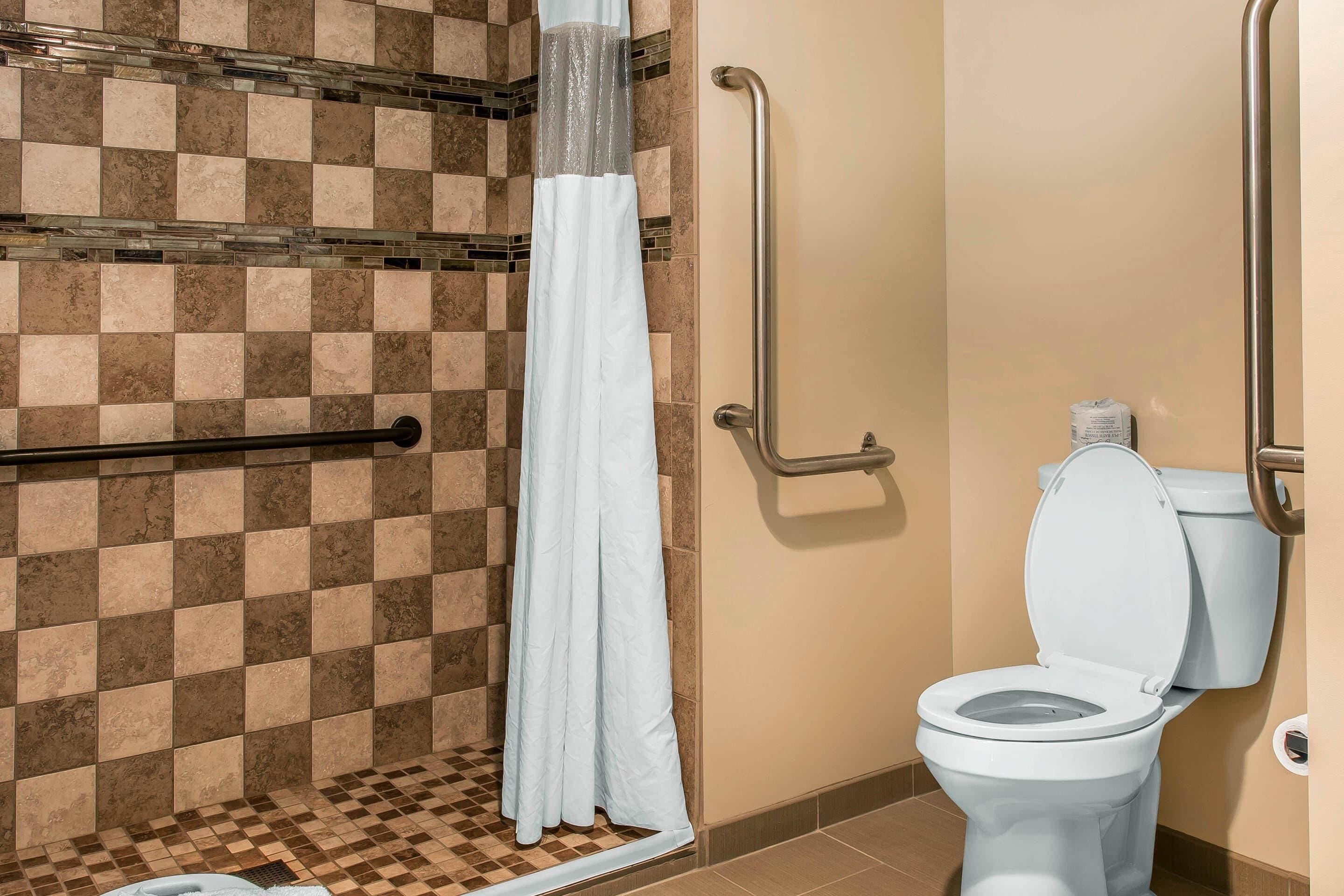 A bathroom with a checkered tile wall, a white shower curtain, a white toilet, and a grab bar.