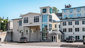A hotel with a modern design, featuring a prominent tower with signage, a stone facade, and multiple windows. - Quality Inn & Suites Houghton Downtown (Houghton)