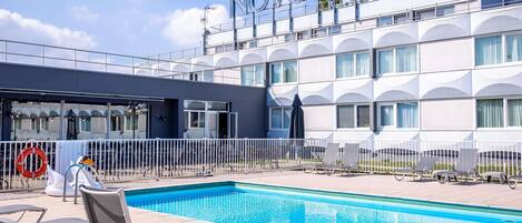 Un hotel con zona de piscina, mobiliario exterior y una arquitectura moderna distintiva.