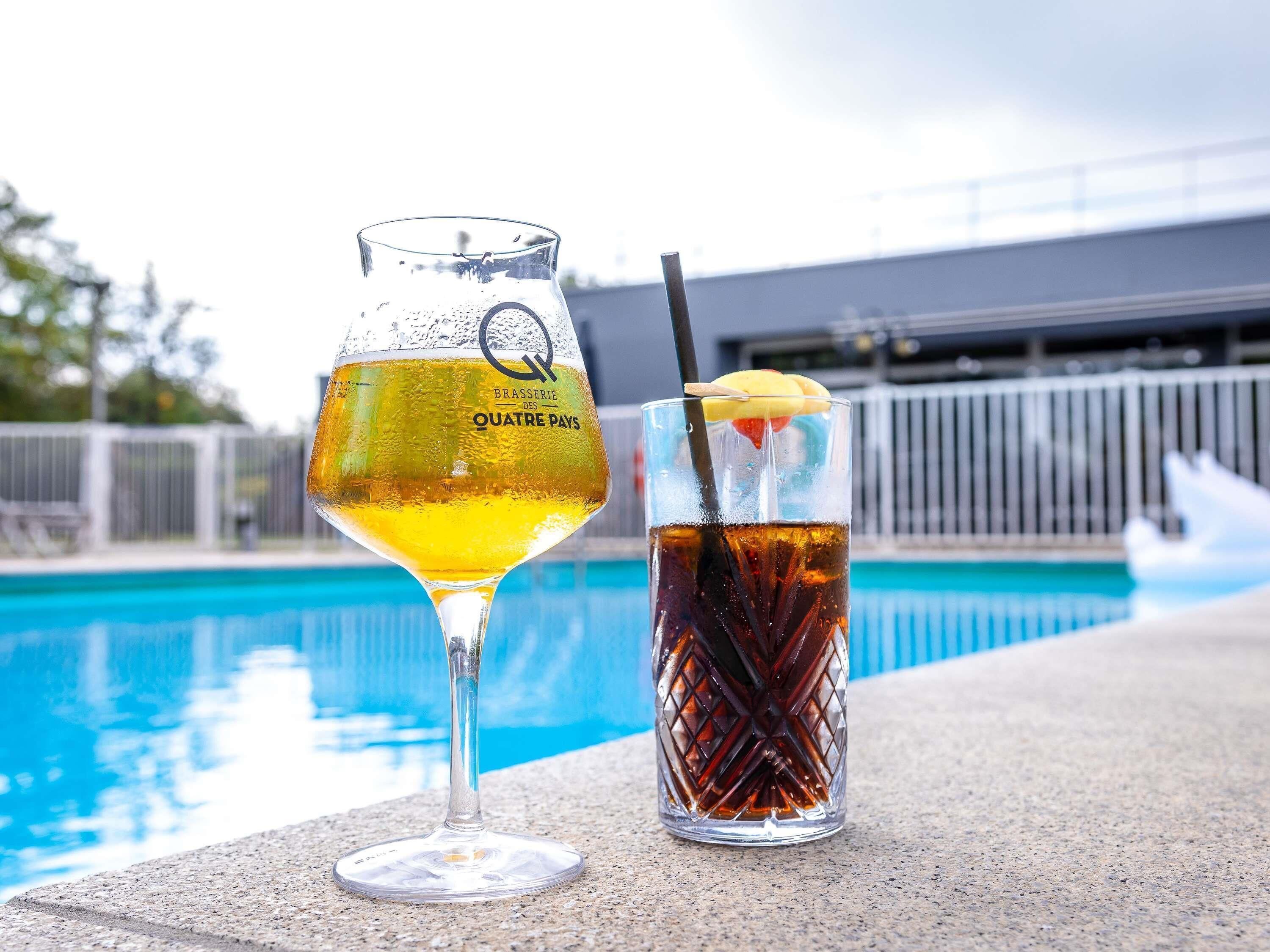 Ein Bierglas und ein Cola-Glas am Pool.