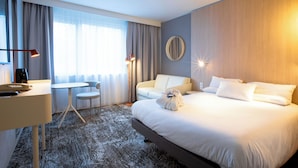 Une chambre d’hôtel avec un grand lit, un bureau avec une chaise, une petite table et un canapé.