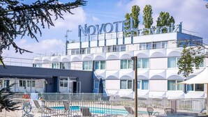 Un hôtel appelé « NOVOTEL », doté d’une piscine, d’un espace extérieur aménagé et d’une architecture moderne.