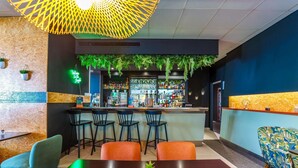 Un espace bar comprenant un comptoir, des tabourets et un coin salon avec une table et des chaises.