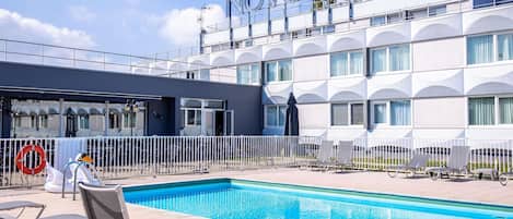 Un hotel con zona de piscina, mobiliario exterior y una arquitectura moderna distintiva.