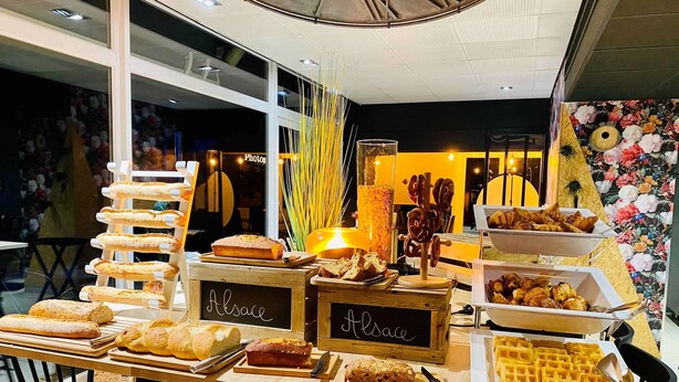 Une table de buffet proposant une variété de produits de boulangerie, notamment du pain, des pâtisseries et des gaufres.