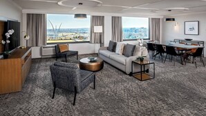 A modern hotel room with a living area, dining space, and large windows offering a city view. - Sheraton Pentagon City Hotel (Arlington)