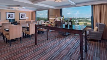 Une chambre d’hôtel comprenant un coin repas, une vue sur la ville et un bar avec des bouteilles et des verres.