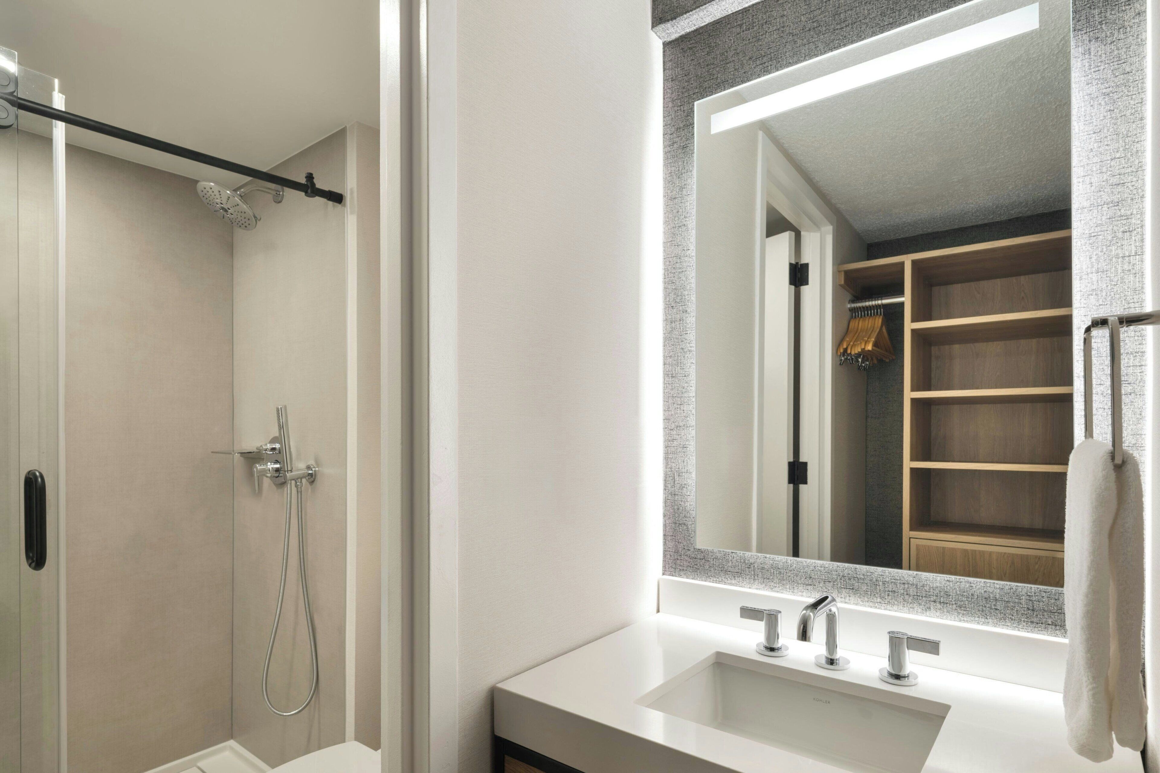 Un baño con ducha a nivel, un espejo grande y un tocador con lavabo.