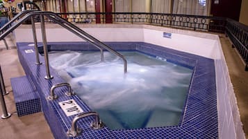 A hot tub with a metal ladder and railings, surrounded by a tiled floor.