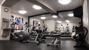 A gym with various exercise equipment, a water dispenser, and a clock on the wall. - Holiday Inn Fargo by IHG (Fargo)