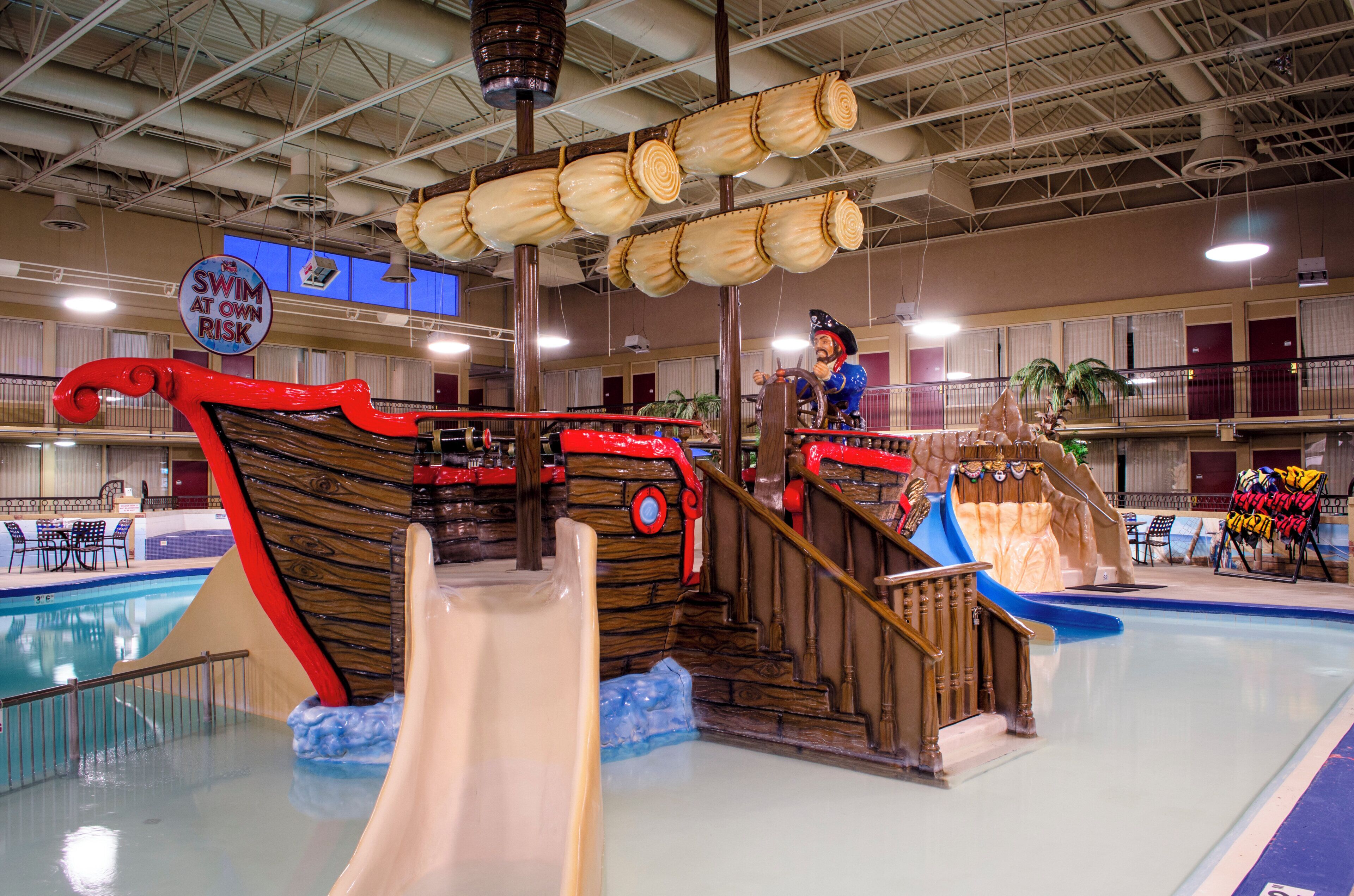 An indoor water park with a pirate ship-themed play area, including slides and a pool.