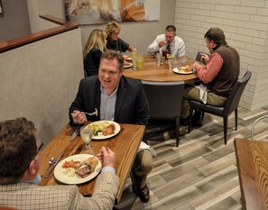 Un grupo de personas cenando en una mesa redonda en una habitación con suelo de diseño espiga.