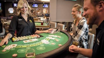 A casino table with a dealer and customers.
