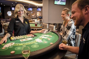 A casino table with a dealer and customers.