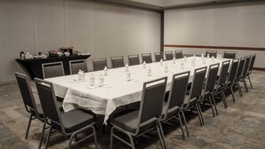 Une salle de conférence équipée d’une longue table, de chaises et d’un espace buffet où sont servis des plats et des boissons.