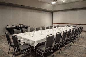A conference room with a long table, chairs, and a buffet area with food and drinks. - Holiday Inn Fargo by IHG (Fargo)