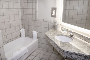 A bathroom with a bathtub, a sink, and a mirror.