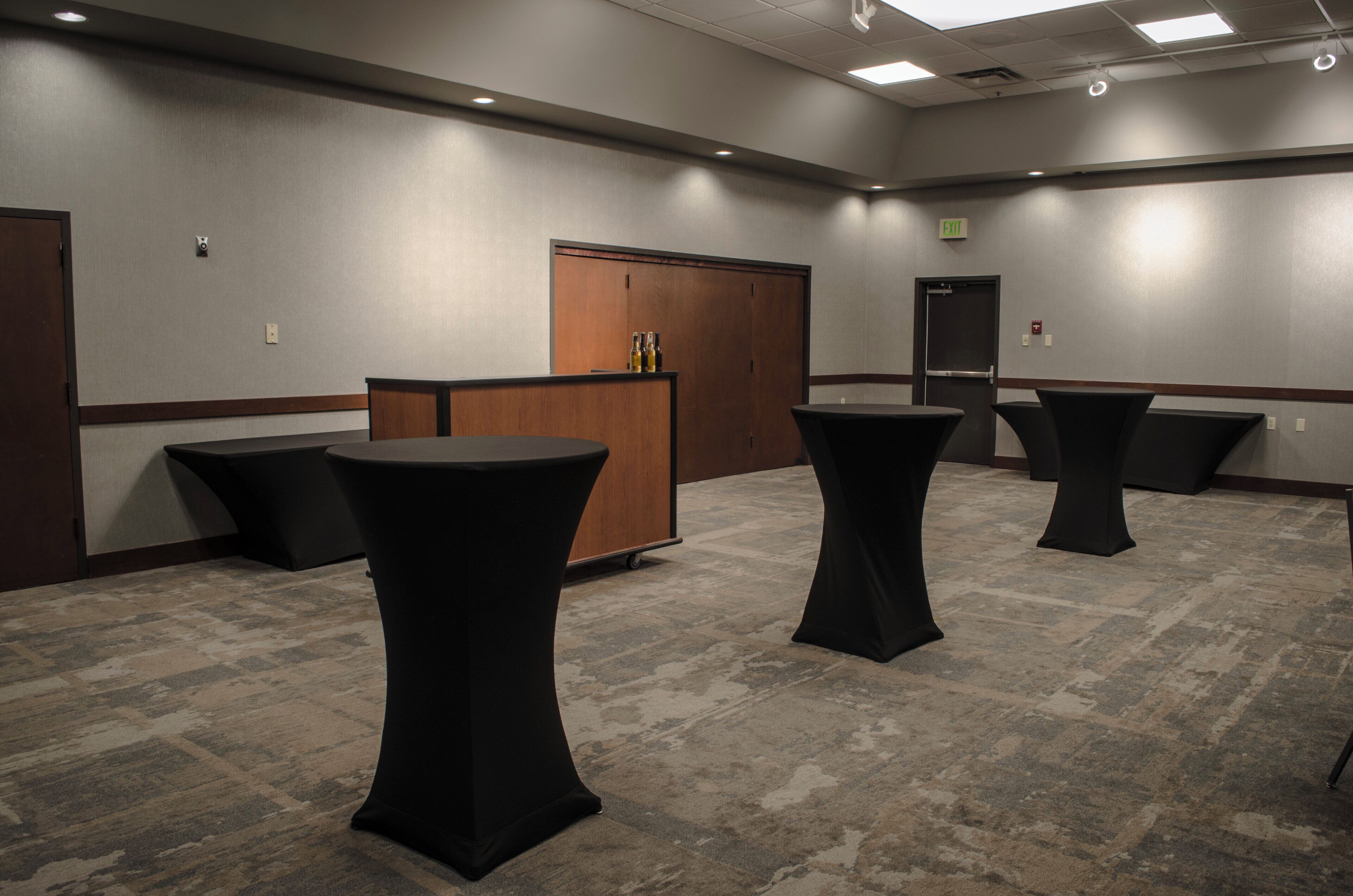 A conference room with a wooden cabinet, a podium, and three round tables.