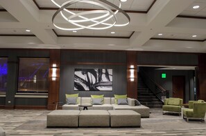 A lobby with a modern design, featuring a sectional sofa, a round coffee table, and a large abstract painting on the wall.
