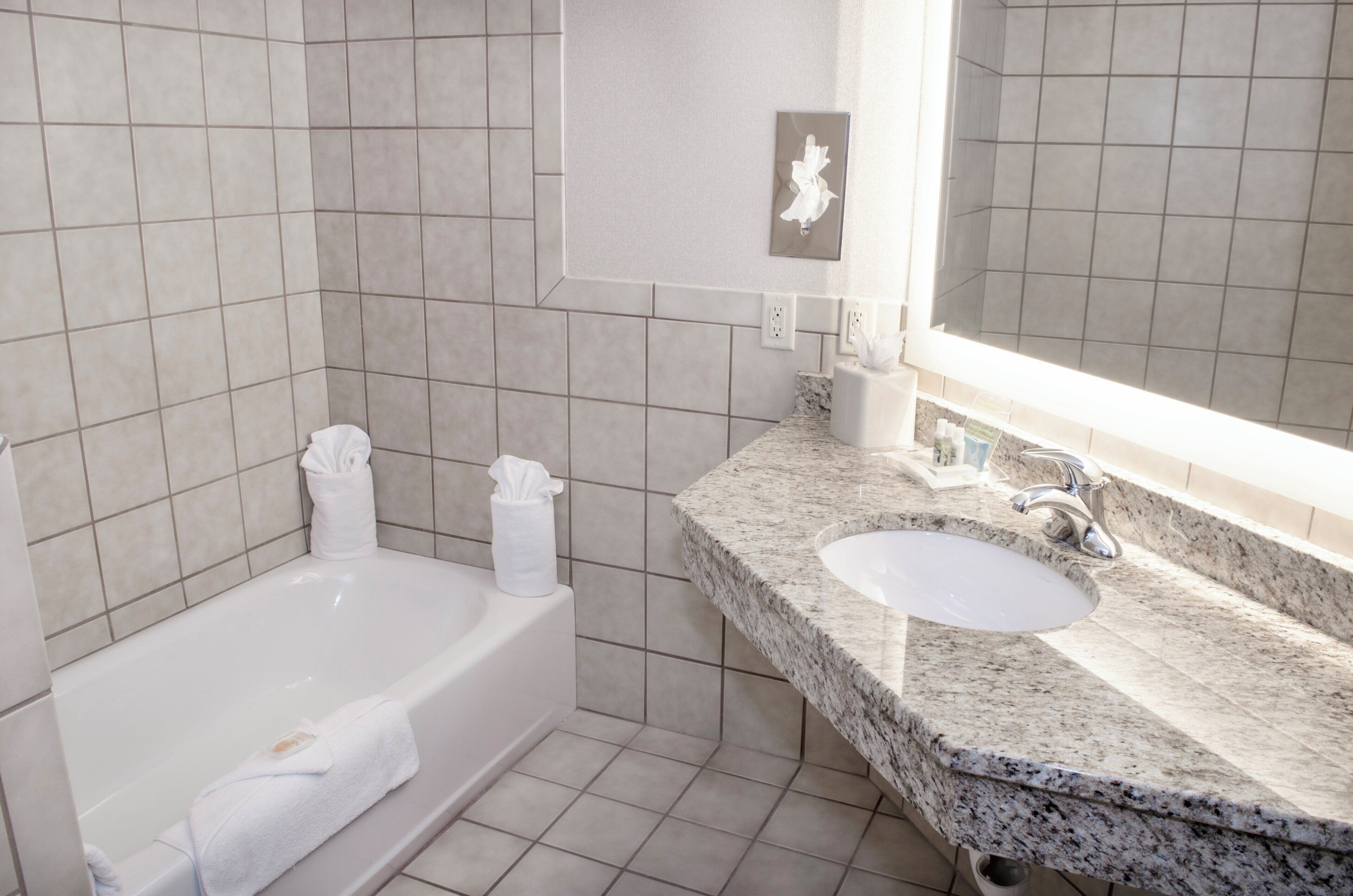 A bathroom with a bathtub, a sink, and a mirror.