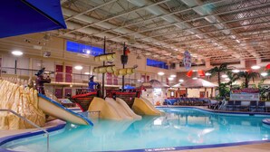 Une piscine intérieure avec des toboggans et un espace bar.