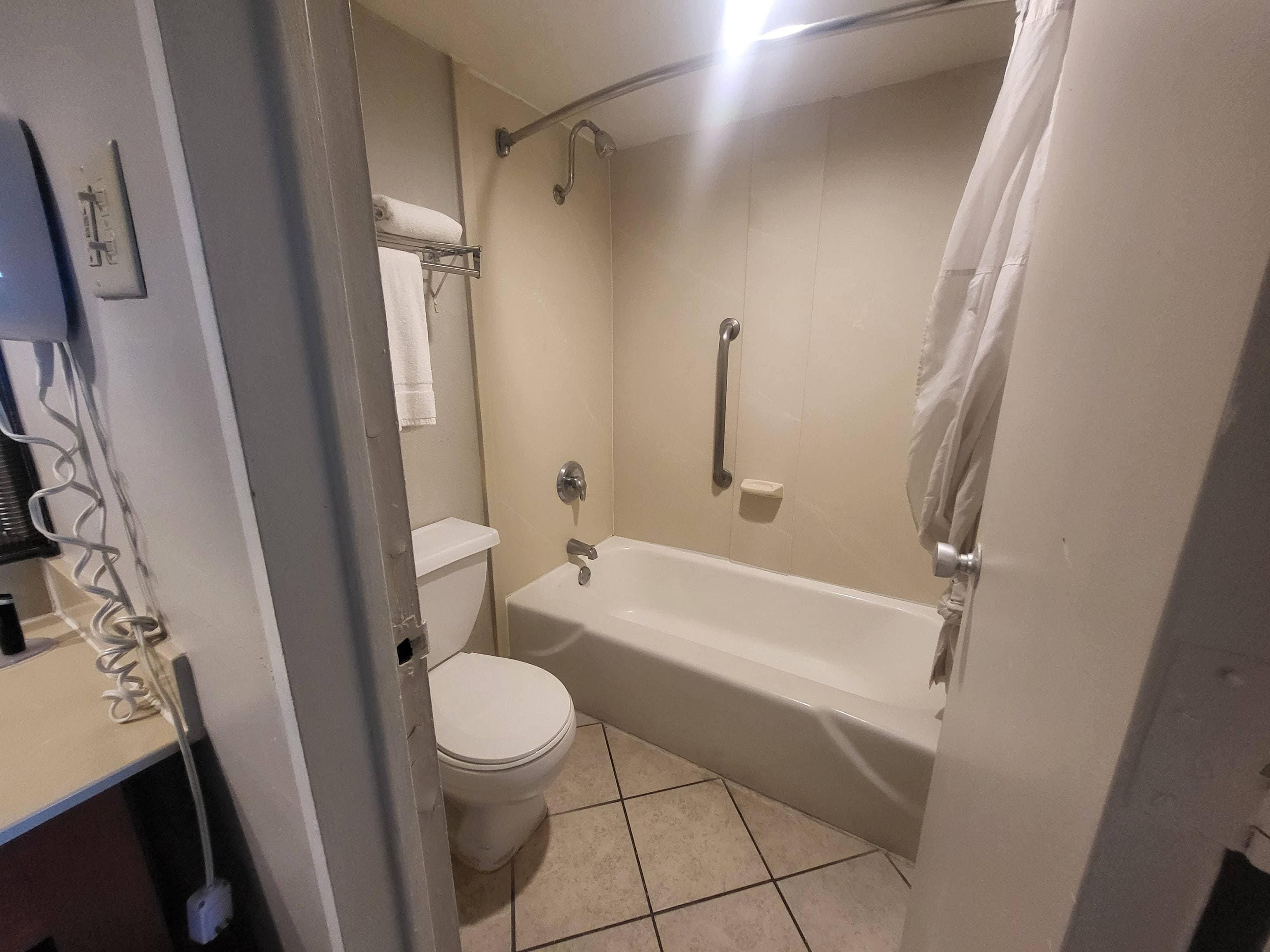 A bathroom with a bathtub, toilet, and a shower curtain.